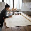 Project timeline and scope document on studio table with designer reviewing phases and budget ranges via video call